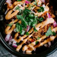 Carnitas Taco Bowl · Achiote Rice, Black Ranchero Beans, Crispy pork topped with red onions, cilantro, and sun-dr...