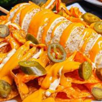 Elote Chorreado · a whole corn with mayo, cotija cheese and chili on top of rancheritos and dorito nachos with...
