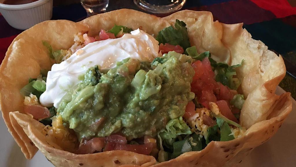 Taco Salad Cazuela · A bowl-shaped flour tortilla deep-fried and filled with beef or chicken, lettuce, tomatoes, guacamole and sour cream.