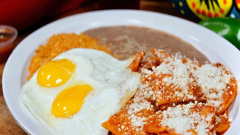 Chilaquiles · Tortilla chips cooked in red sauce and sprinkled with Mexican cheese. Served with two eggs, rice, and beans.