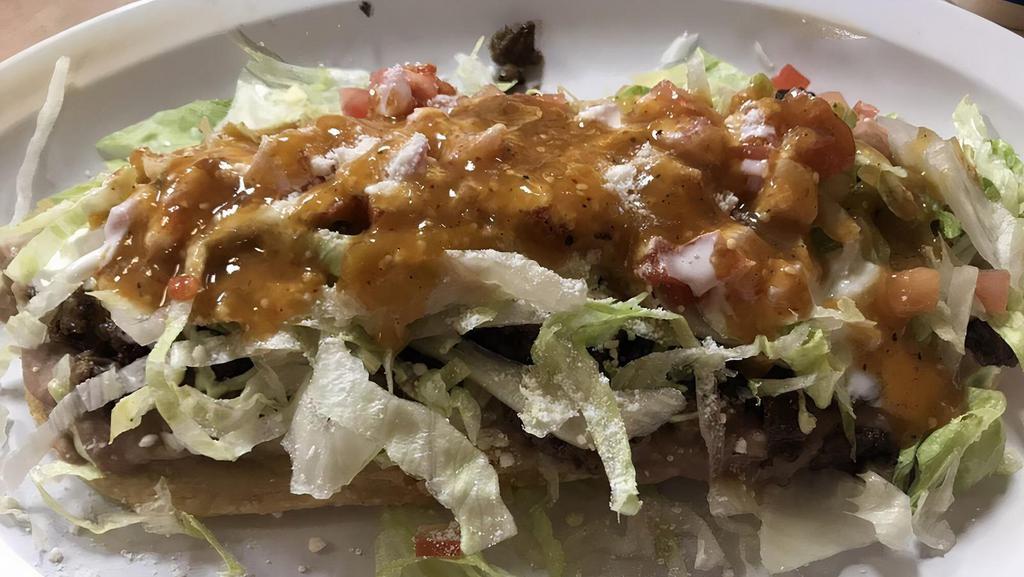Huarache · Similar to sopes, huaraches are a deep fried masa base topped with your choice of meat, lettuce, tomato, sour cream, and cheese.