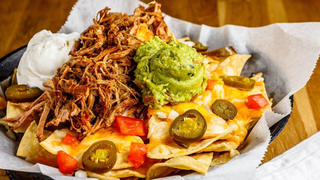Green Chili Pork Nachos · Slow, tender-roasted, green chili with or without  pulled pork on top of tri-colored tortilla chips. Topped with onions, tomatoes, olives, jalapeños, twin cheeses, guacamole and sour creamor.