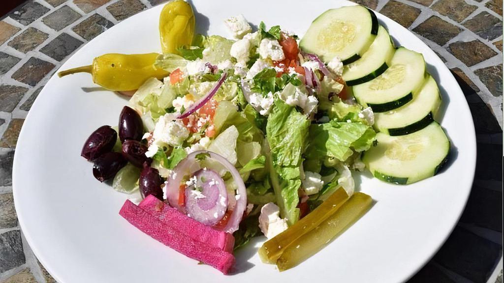Greek Salad · A bed of salad with tomato, cucumber, onions, kalamata olives, feta, and assorted Mediterranean pickles. Served with warm pita and your choice of dressing.