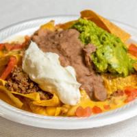 Super Nachos · Spicy queso, chips, sour cream, beans, guacamole, beef and tomatoes.