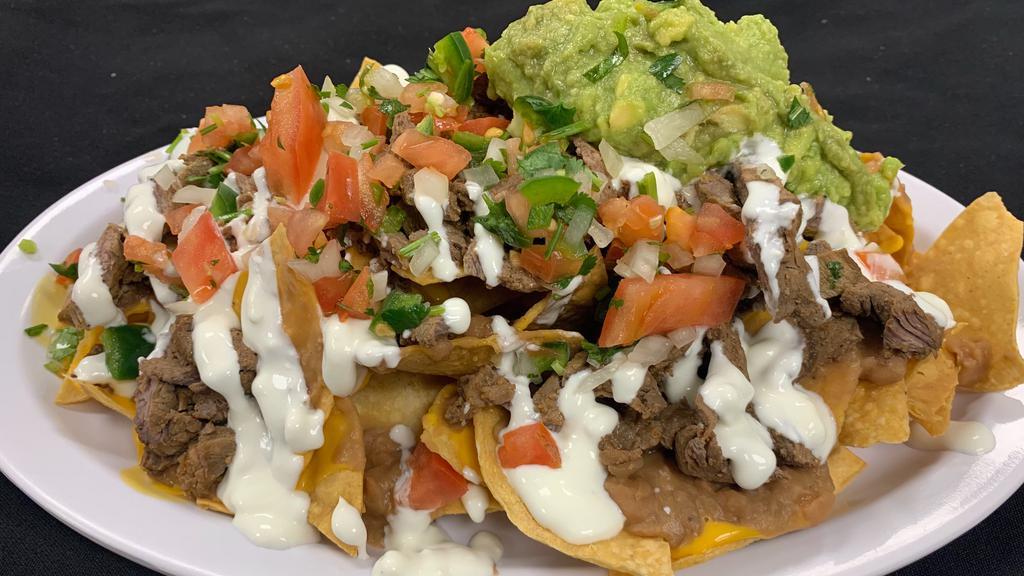 Al Pastor Nachos · Al Pastor meat (marinated pork), chips, beans, nacho cheese, guacamole and sour cream