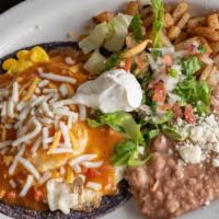 Huevos Rancheros · Two eggs over a home made blue corn tortilla. Smothered in green chile with side of beans an...