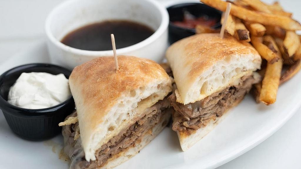 French Dip Sandwich · Slow roasted, thinly sliced beef tip topped with melted provolone cheese piled high on a Parmesan grilled ciabatta bun and served with a side of horseradish cream and Rosemary Au Jus.