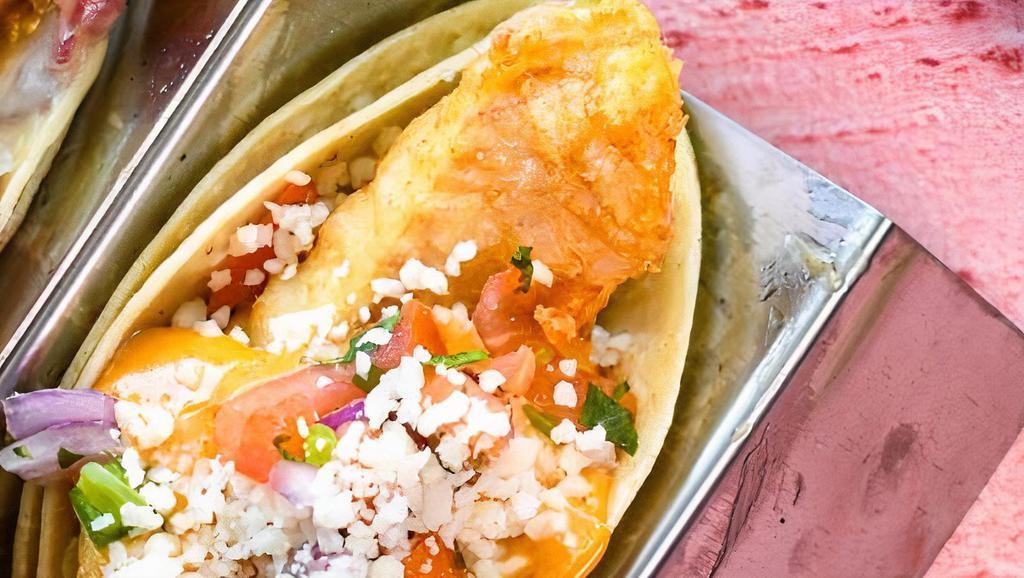 Fish Tacos · Three lush tacos loaded with beer battered cod, pickled red onion, napa slaw, tomatoes, chipotle aioli, jalapeno, cotija, cilantro.