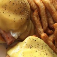 Eggs Benedict · English muffin topped with poached eggs, sliced ham and hollandaise sauce, served with hash ...