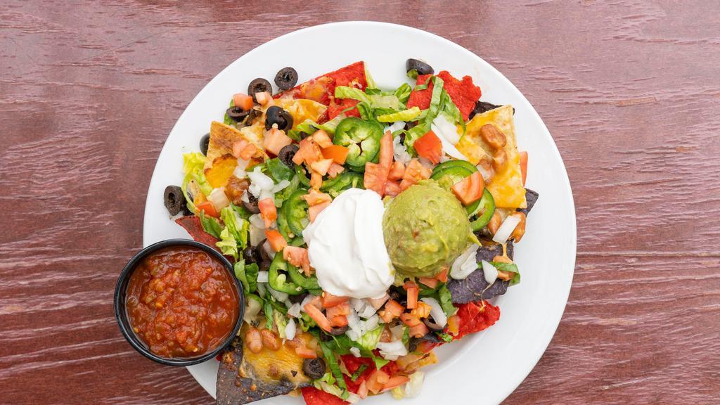 Full House Nacho · Melted cheese, sliced olives, lettuce, tomatoes, guacamole, onion, beans, jalapeno, sour cream and salsa.  On a bed of corn chips.