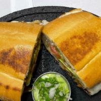 Torta Hawaiina · French bread with beans, ham, pineapple, milk cheese, avocado, onions, chipotle sauce, and m...