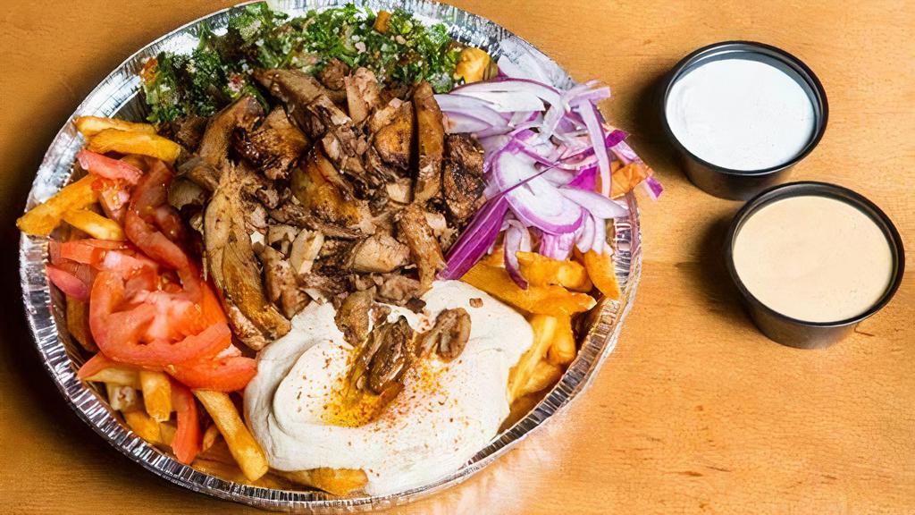Loaded Chicken Shawerma Fries · Topped with chicken shawerma slices, fresh tabbouleh, hummus, tomatoes, and red onions. Seasoned and served with our secret fry sauce.
