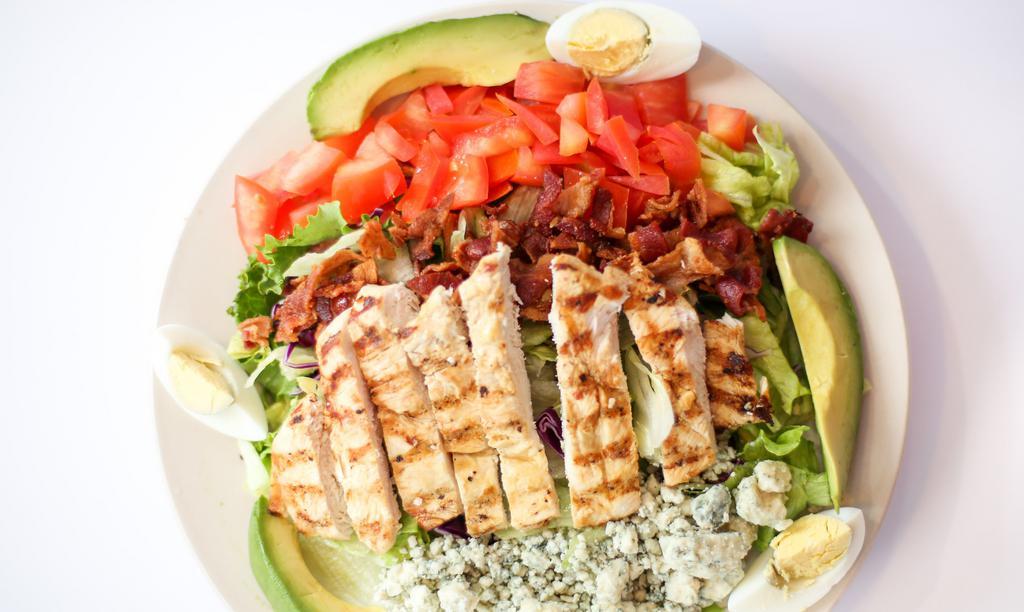 Cobb Salad · Mixed greens topped with sliced grilled chicken strips, crumbled blue cheese, bacon, tomatoes, avocado wedges and hard boiled egg.