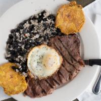 Bistec A Caballo · Thinly cut steak, grilled with mojito sauce and topped with fried egg. Served with congri an...