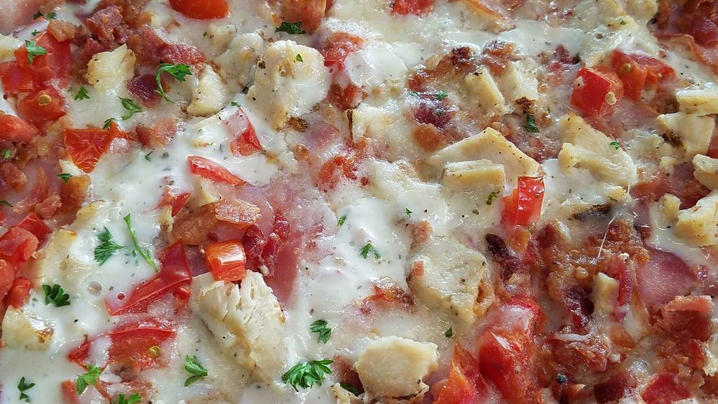 Chicken Bacon Ranch Pizza · Garlic chicken, bacon crumbles, Canadian bacon and cooked tomatoes on our buttermilk ranch base with a drizzle of ranch on top.