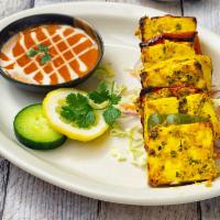 Paneer Tikka · Paneer marinated in yogurt, turmeric, and spices, cooked in tandoor, and served over a bed o...