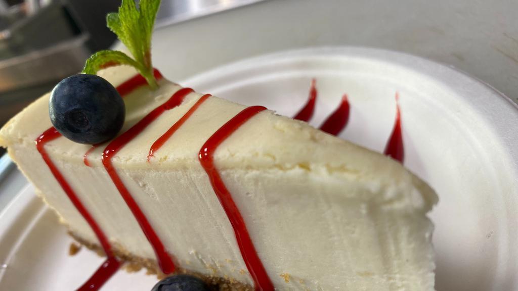 Traditional Cheese Cake · 1 Pc cheese cake with raspberry sauce and strawberries.