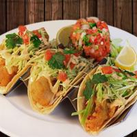 Tacos De Pescado · Three soft tacos with battered and fried fish, topped with cabbage, a creamy mild sauce, tom...