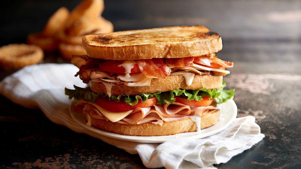 Clubhouse Sandwich · Sliced turkey, ham and smoked bacon topped with provolone and cheddar cheese, fresh greens, tomatoes and garlic aioli on toasted sourdough