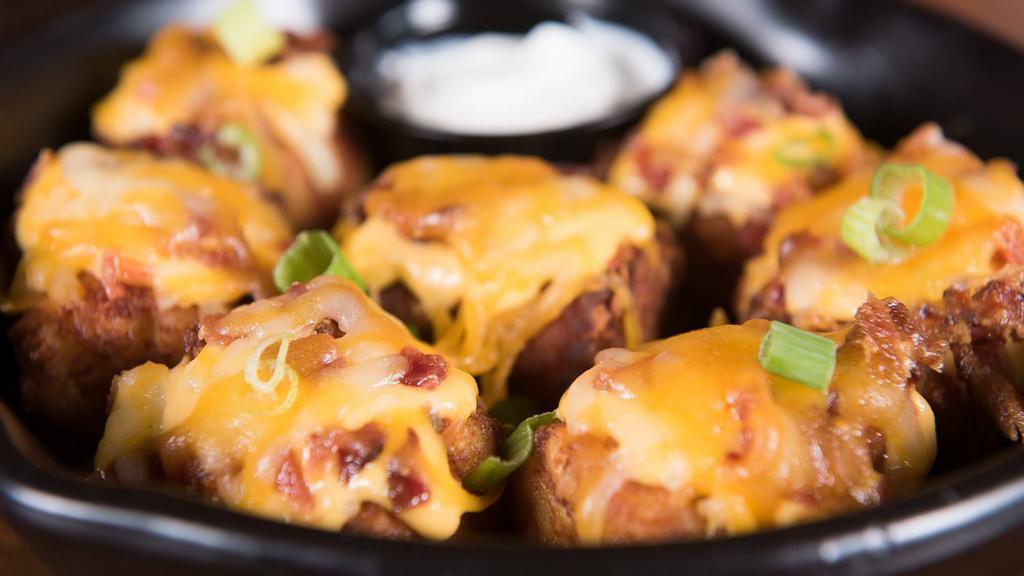 Totchos · Our jumbo tater tots stuffed with serrano peppers, bacon, and cheddar. Topped with bacon, green onions, cheddar, pepper jack, melted cheese, and sour cream.