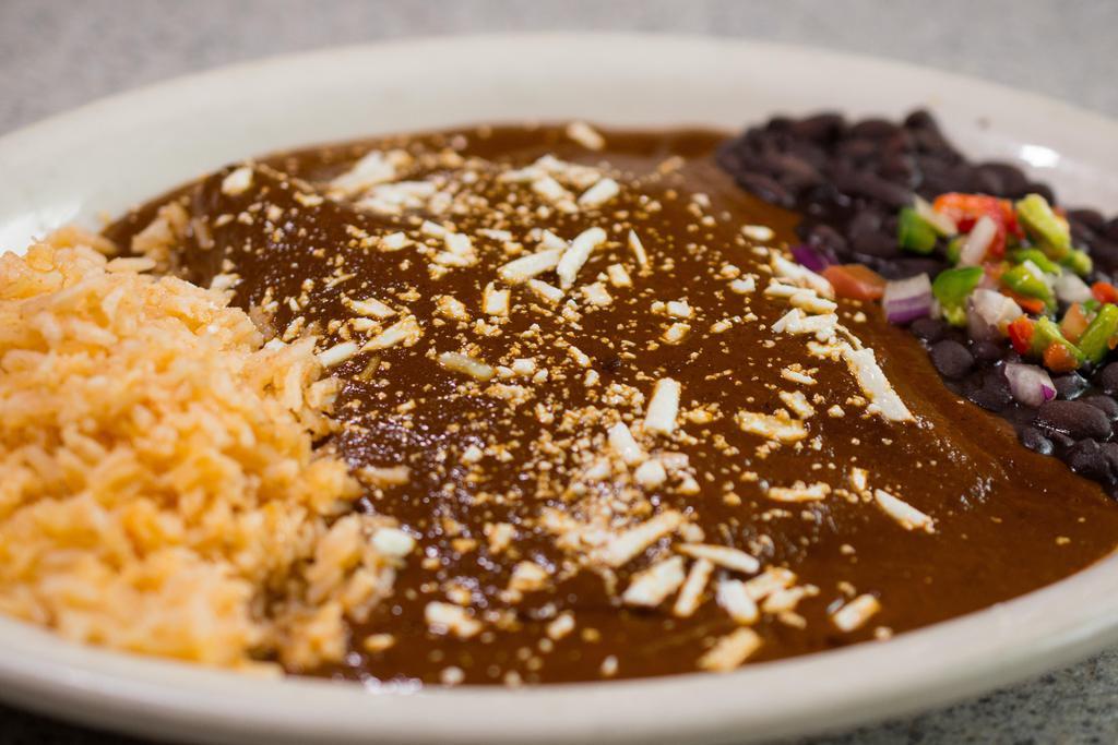 Mole Enchiladas · Two corn tortillas rolled up with shredded chicken, topped with cotija cheese and smothered in our house made mole sauce made with ancho pepper and a touch of chocolate and cinnamon. Served with rice and black beans.