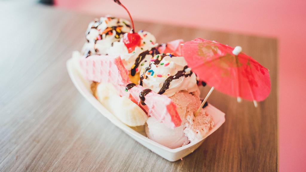 Banana Split · Banana split in half. Three scoops of ice cream with waffle cookies on the side topped with whipped cream chocolate syrup and a cherry.