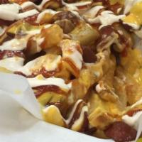 Salchipapas · French fries covered in nacho cheese, fried Winnie, bacon, ketchup, sour cream, and cotija c...