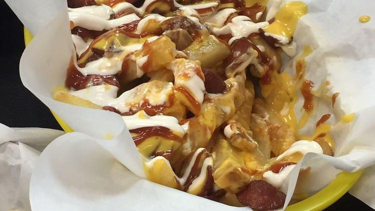 Salchipapas · French fries covered in nacho cheese, fried Winnie, bacon, ketchup, sour cream, and cotija cheese.