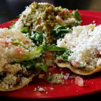 Tostadas (3) · Flat fried corn tortilla topped with spread beans, lettuce, tomatoes, crumbled fresh cheese,...