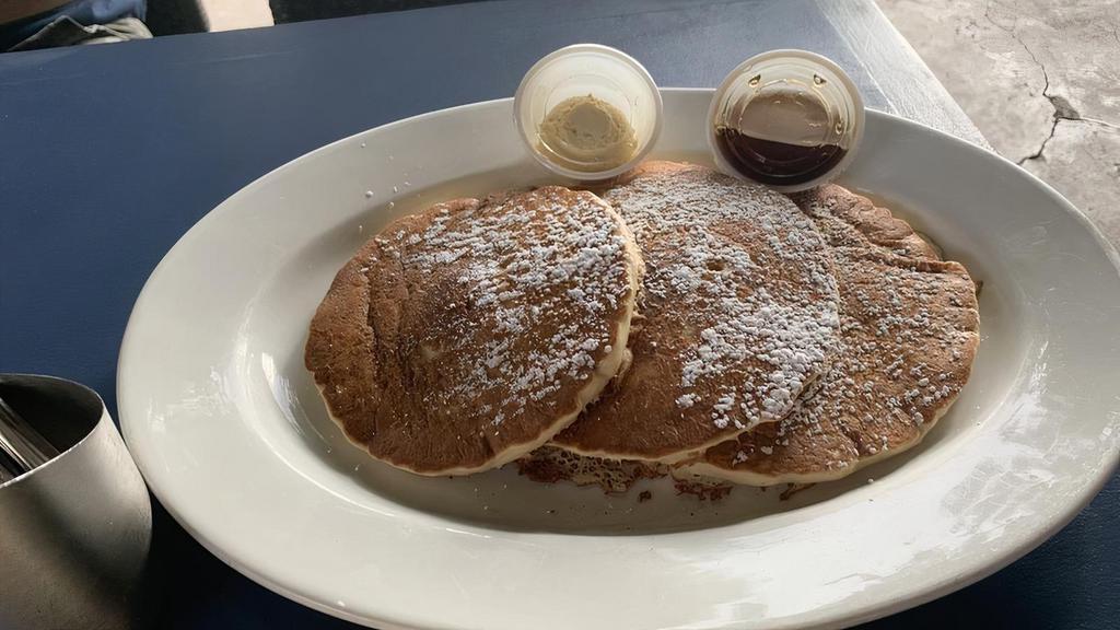 Original Sweet Cream Pancakes · Three fluffy homemade sweet cream pancakes topped with powdered sugar and served with maple syrup and sweet butter.