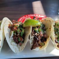 Carne Asada Tacos · Carne asada–grilled steak which has been marinated with lime and garlic. Served with warm to...
