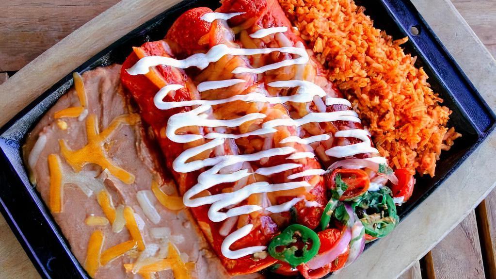 Ultimate Enchilada Combo · Seasoned ground beef, chicken breast & pork carnitas wrapped up in three thick corn tortillas, smothered in red or green enchilada sauce, Cheddar & Jack cheese & sour cream. Served with Mexican rice and refried beans.