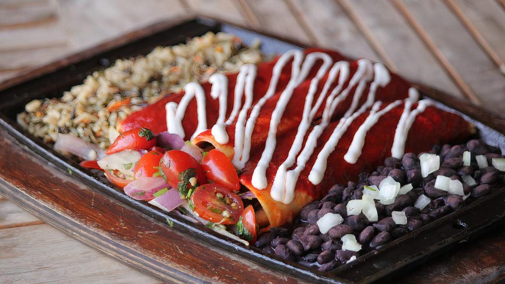 Vegan Enchiladas · Sauteed red & green bell peppers, onions, mushrooms, vegan Cheddar cheese wrapped in three thick corn tortillas, smothered in red or green enchilada sauce. Served with vegan sour cream, cherry tomato pico de gallo, black beans & wild rice.
