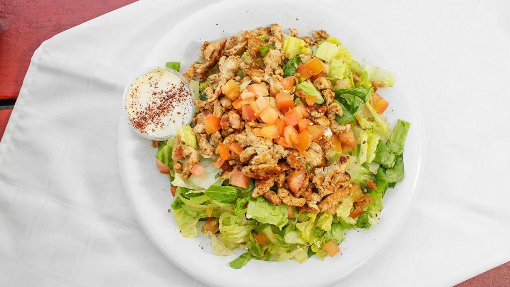 Chicken Shawarma Over Salad · Marinated and seasoned white breast chicken grilled served over mixture of  lettuce, tomatoes, cucumbers mixed with our house Mediterranean dressing. Comes with Creamy Garlic Sauce on the side.