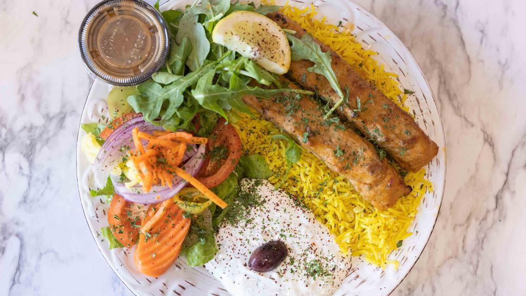 Chicken Kebab Over Rice · Two skewers of iraqi kebab chicken comes with the sauce of tzatziki and house salad dressing garlic sauce and hot sauce over basmati rice.