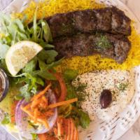 Beef Kofta Kebab Over Rice · Two skewers of yummy kebab Kofta over basmati rice house salad garlic sauce and hot sauce sa...