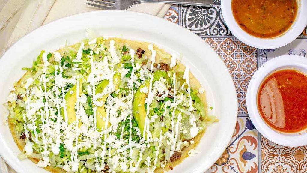 Huaraches · 10 inch long Corn Masa tortilla topped with re-fried pinto beans, poblano green salsa, lettuce, queso fresco, crema, cilantro, and sliced avocado.