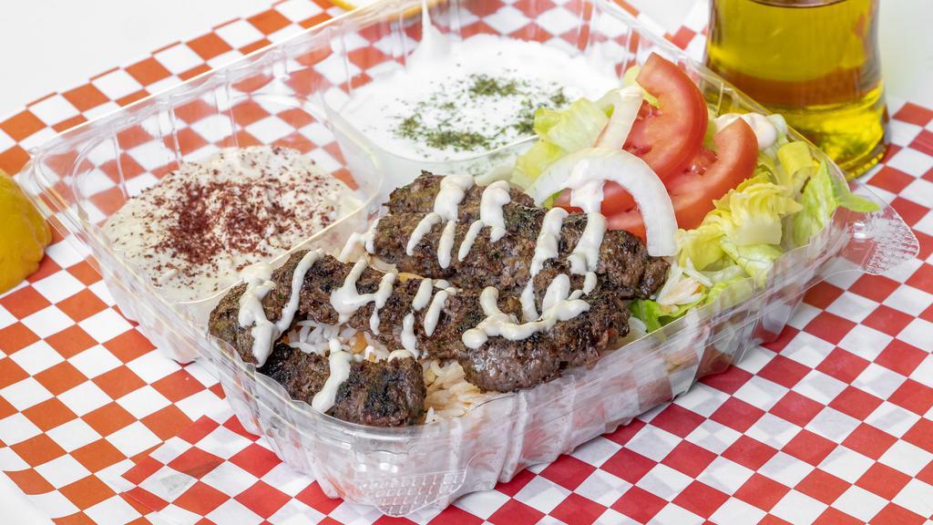 Kafta Kebab Combo · Ground beef with chopped onion, parsley, and season cooked on the top griddle, on a bed of basmati rice topped with house garlic sauce, two sides, hummus, tzatziki, and some green next to rice. Extra meat for an additional charge.