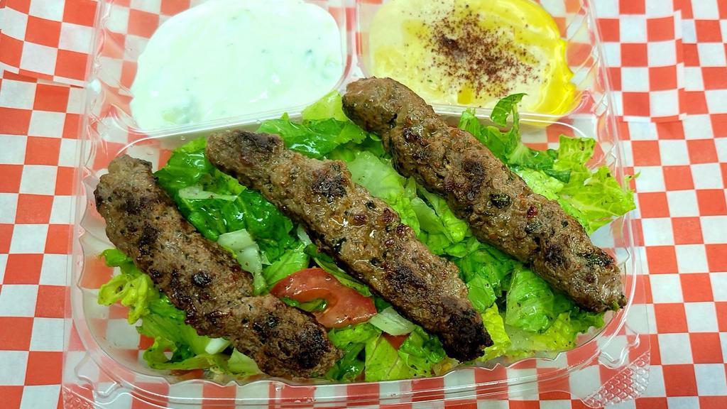 Kafta Kabab Over Salad  · Kafta Kabob over Middle Eastern salad with two sides of hummus and tzatziki