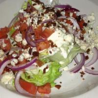 Wedge · Iceberg lettuce, bacon, tomatoes, red onions, blue cheese crumbles, and bleu cheese dressing.