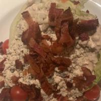 Wedge Salad · Iceberg lettuce, bleu cheese dressing, bleu cheese crumbles, bacon and cherry tomatoes.