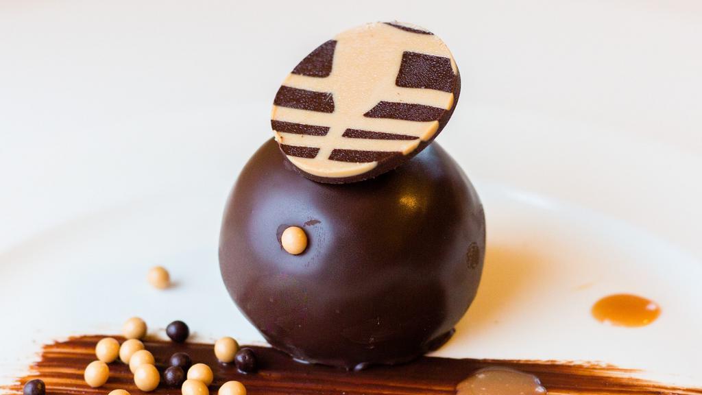 Bourbon Ball · Dense chocolate cake soaked in bourbon and glazed with dark chocolate ganache. Served with a sides of house-made caramel and chocolate sauce