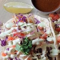 Chicken Tinga Tacos (2) · Spicy red chile, onion, and tomato-braised chicken, cabbage, avocado crema, cotija cheese, a...