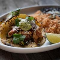 Ancho Chicken Tacos · Two tacos with housemade corn tortillas—hand-pressed daily. Served with Spanish rice and cum...