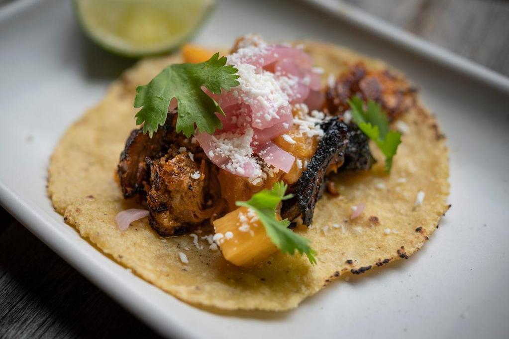1 Taco Carnitas · Achiote pork braised in banana leaves, caramelized pineapple salsa, red onion escabeche, cotija cheese, cilantro.
