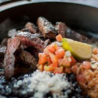 Steak Fajitas · All natural, hormone free skirt steak served with Spanish rice, cumin black beans and carame...