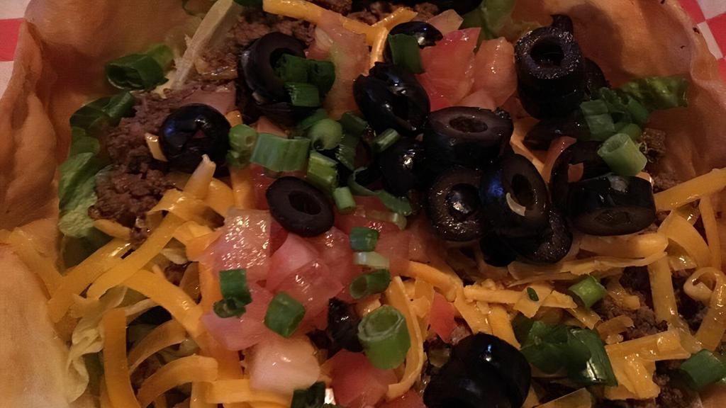 Taco Salad · It's a Fiesta time! Ground beef, shredded cheddar cheese, fresh diced tomatoes, black olives, sour cream, topped with green onions, all in a taco shell. Salsa served on the side.