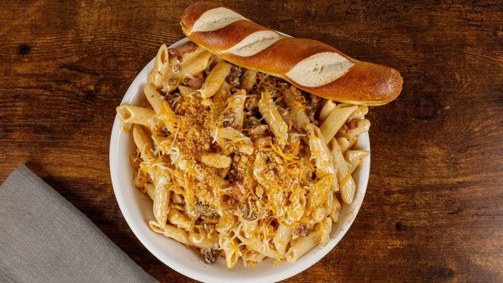 *New* Cheeseburger Mac Mac · The best of both worlds!  Sautéed ground beef with chopped bacon, caramelized onions and creamy cheese sauce tossed with penne pasta and our spicy boom sauce.  Topped with tomatoes, shredded cheese and toasted breadcrumbs.  Served with pretzel bread.