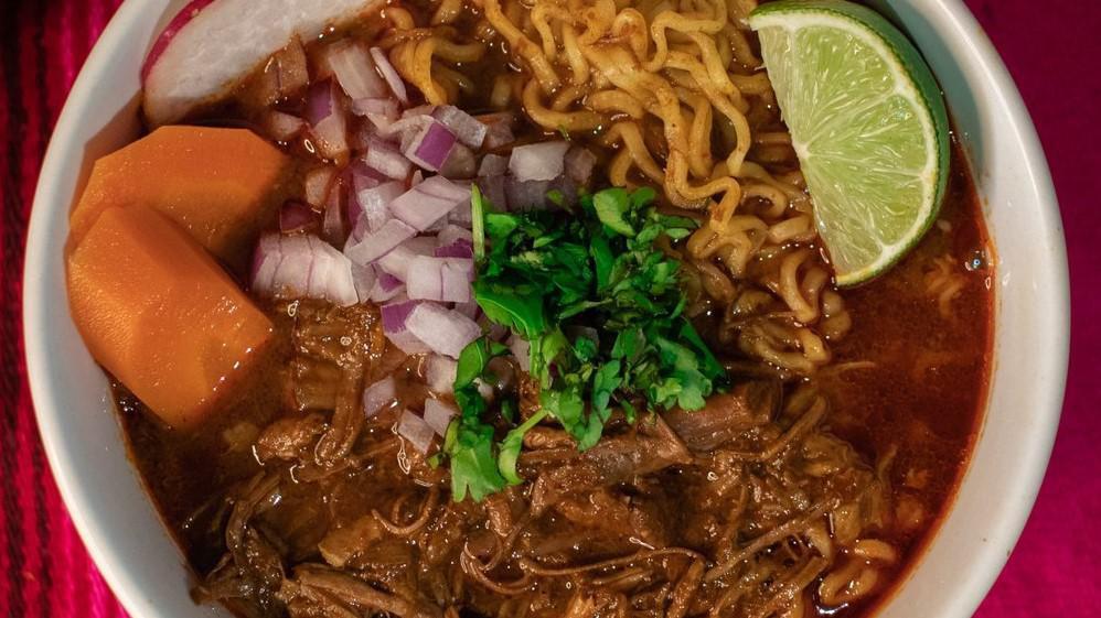 Birria Ramen · Ramen noodles in consome topped with birria, cilantro, onions, pickled carrots, and lime.