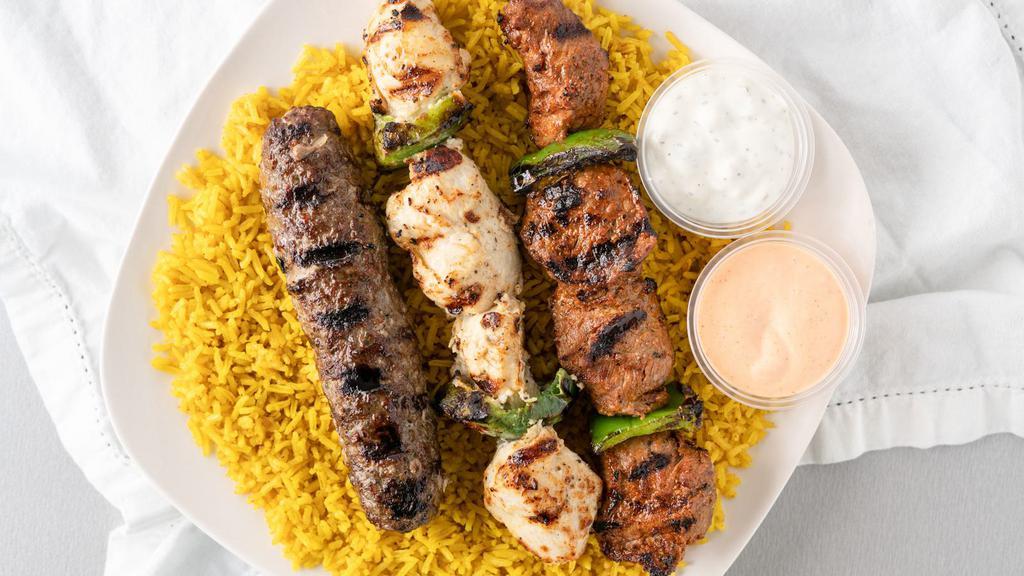 Combo Kebob Platter · Three skewers of fire grilled meats. Lamb skewer, Chicken skewer, and Kafta skewer. Served over a bed of rice, pick a side and sauce to complete the meal.
